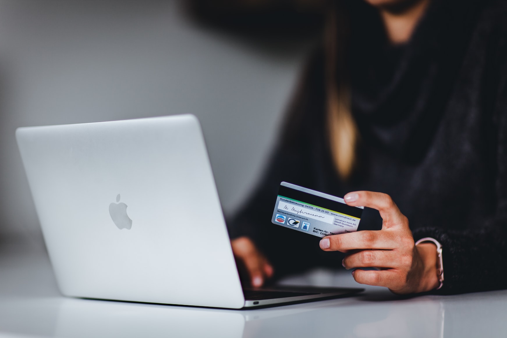 A woman is using her credit card to shop online